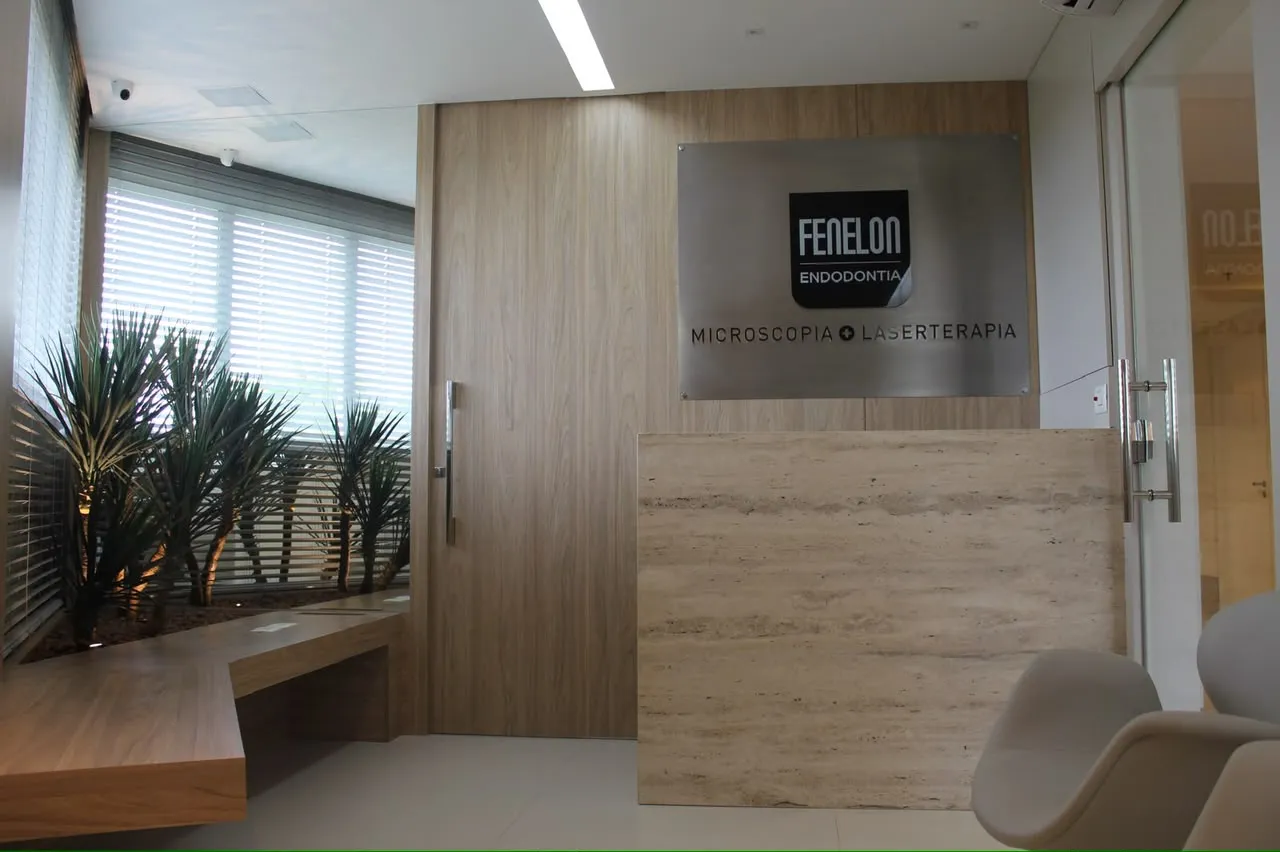 Recepção da Fenelon Endodontia com balcão de pedra, jardim e marca da clínica